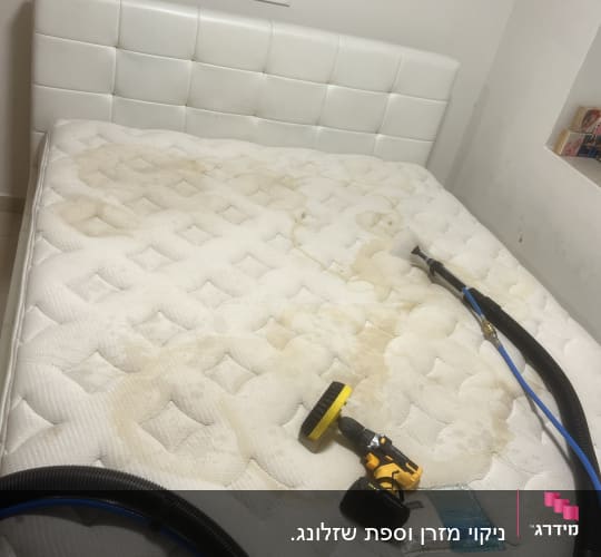 מזרן עם כתמים, מכונת ניקוי צהובה וצינור שחור